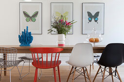 Verschiedene Designerstühle um den Esstisch vor Schmetterlingbildern