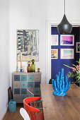 Blue sculpture of coral on dining table and view into corridor with blue wall