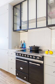 Glass and steel wall units above vintage-style cooker
