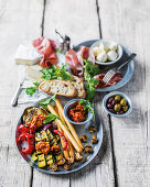 An appetizer tableau with grilled vegetables and bread sticks