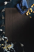 A wooden board framed by a garland and various dessert ingredients (top view)