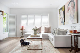 White leather corner sofa and coffee table with marble top in bright living room