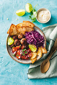 Lunch Bowl mit würzigen Lammhackbällchen, Tomaten, Rotkohl, Ananas und Tortilla