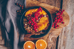 Autumnal porridge with cinnamon, hazelnuts, orange slices, redcurrants and mango