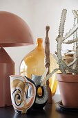 Mid-century modern arrangement of vases, designer lamp and cactus