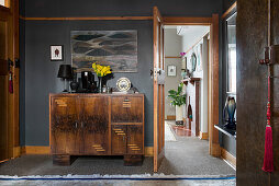 Black lamp and vases on Art Deco cabinet against black wall