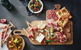 An antipasti plater with focaccia, pickled chillis, grissini, Prosciutto, olives, gorgonzola, salami, sopressa and grilled courgettes