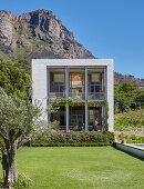 Cubic house with loggia and glass wall against mountain backdrop