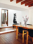 Old designer chairs at wooden table on terracotta-tiled floor