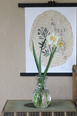 Narcissus in vintage vase in front of picture on torn newspaper
