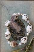 Circlet of threaded quail eggs and beads on old book