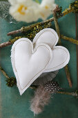 Two fabric hearts and spotted feather on twigs