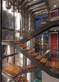 Open-plan, wood and steel staircase above pool in modern architect-designed house