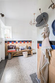 Coat hooks and wooden bench in half-height foyer with terrazzo floor