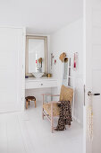 Antique chair, mirror and ladder in front of small washstand in white bathroom