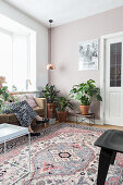 Zimmerpflanzen in hellem Wohnzimmer mit Teppich, Frau sitzt auf Sofa