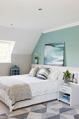 Double bed and pale green wall in attic bedroom