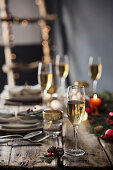 Champagnergläser auf weihnachtlich gedecktem Holztisch