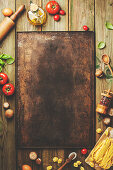 Cooking background: empty rustic baking sheet and italian ingredients