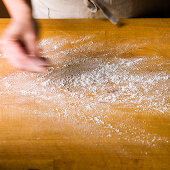Dusting flour on a butcher block cutting board