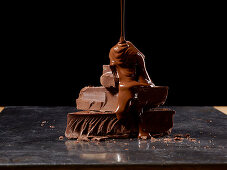 Chocolate sauce being poured on stack of chocolate