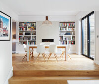 Steps leading into dining room with fitted shelves in niches flanking fireplace