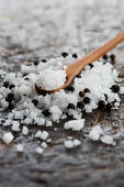 Sea salt and black peppercorns with a wooden spoon