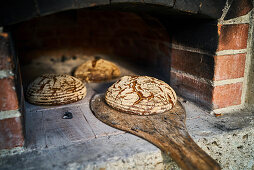 Crusty Fürstätt bread being taken from a wood-fired oven