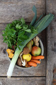 Leeks, mushrooms, pears, apples, carrots and ginger in a bowl (top view)