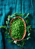 Peas in a wooden bowl with a leaf wreath