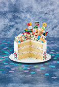 A buttercream cake with sprinkles, topped with popcorn and sweets