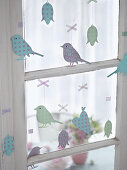Easter arrangement of metal pendants in window (birds, flowers, hearts)