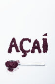 Acai berry powder: on a spoon and lettered against a white background