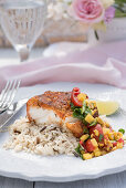 Breaded cod fillet with rice and salsa on a summer table outside