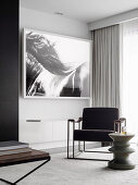 Polsterstuhl und Designer-Beistelltisch vor schwarz-weiße Aufnahme an der Wand
