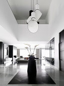 Designer pendant lamp over a round table with an orchid in an open living room with double room height