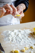 Italian chef making fresh homemade gnocchi pasta rolling on a fork and flour on the wooden board