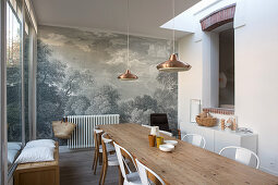 Long wooden table and chairs in dining room with mural wallpaper