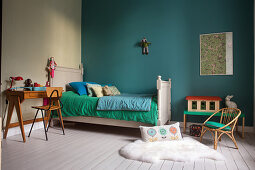 Bed, desk and chair in child's bedroom with turquoise wall