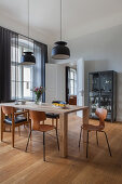 Designer chairs around wooden table in dining room with pale grey wall