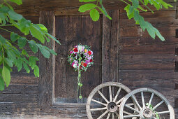 Türkranz aus Salbeiblättern, Dahlien, Phloxblüten und grünen Lampionblumen, daneben alte Holzräder