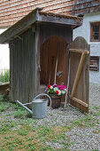 Holzkübel mit bunten Blumen im Geräteschuppen