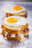Croque Madame; Ham and Gruyere Cheese Grilled Sandwich with Herbed Aioli and Bechamel Sauce Topped with a Sunny Side Up Fried Egg