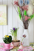 Kalanchoe and crocuses planted in teacups and vase of pussy willow decorated with feathers