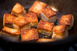 Fried tofu cubes in a wok (close up)