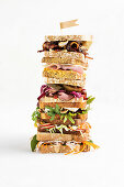 Stacked sandwiches with beef, salmon, cheese, bacon and salad