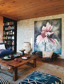 Rustic wooden table and bench in front of large picture on stone wall of living room