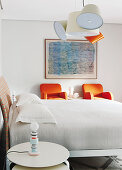 Double bed, side table and two orange armchairs in bright bedroom