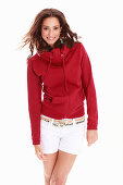 A young brunette woman wearing a red hoodie and white shorts