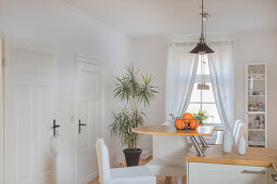 Semicircular breakfast bar on end of kitchen counter in white kitchen of converted dairy